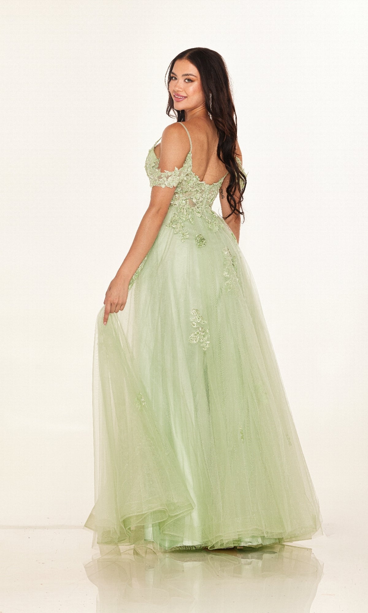 A woman poses against a white background in the Cecilia Couture 2618 long prom dress—an off-the-shoulder light green gown with floral embroidery and layered tulle, creating a dreamy A-line silhouette.